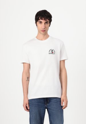 White cotton t-shirt with a round neckline, short sleeves, and black graphic print featuring "TOMMY JEANS NEW YORK CITY" on the chest.