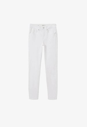 Pull vert clair court avec un col à revers, associé à un jean skinny blanc. Le mannequin porte des talons blancs à lanières, debout devant un fond neutre.
