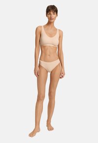 Beige bralette en hoogtaille bikini set. Zachte, gladde stof met gecontourde randen en geen zichtbare naden. Minimalistisch ontwerp en kleur.