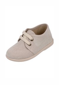 Deportivas de ante beige con punta redonda, cordones bicolor pasados por ojales de latón y suela de goma baja. Textura suave y diseño minimalista.