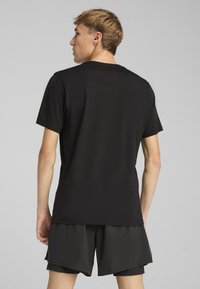 Sort bomulds t-shirt med rund halsudskæring og korte ærmer, med en lige skæring og glat struktur, båret med mørke shorts.