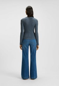 Långärmad, åtsittande ribbad topp i mörkblått, kombinerad med vida, högmidjade jeans i ljusblå denim med två bakfickor.