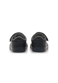 Zwarte leren kinderschoenen met een ronde vorm en klittenbandsluiting, voorzien van een gestructureerde zool en een klein logo op de achterkant.
