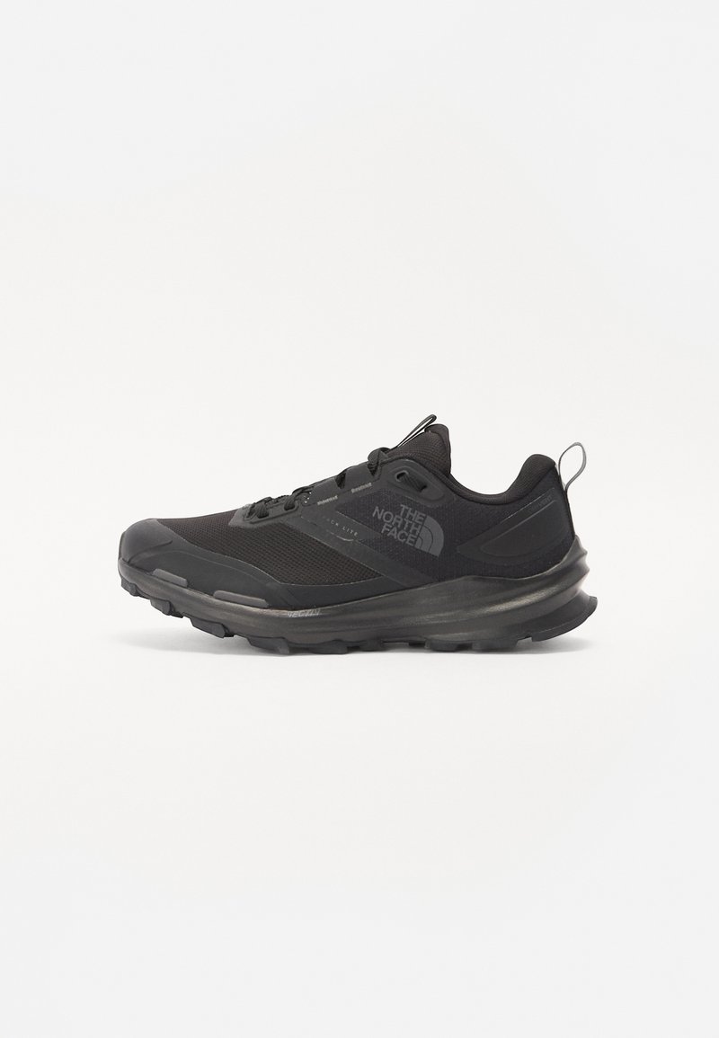 Black athletic shoe with mesh upper, rubber outsole, and padded collar. Features laces, logo on the side, and a textured design.