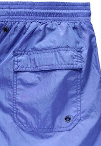 Lilla shorts lavet af letvægtsmateriale med elastisk talje og en lomme med metalaccent. Let glans og struktur synlig.