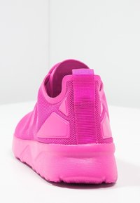 Pink athletic shoes featuring a textured mesh upper, solid rubber sole, and a heel tab for easy wear. Notable angular accents in matching color.