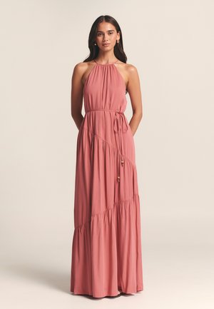 Maxi dress in dusty rose, featuring a halter neckline, cinched waist with tie, tiered skirt, and smooth, flowing fabric.