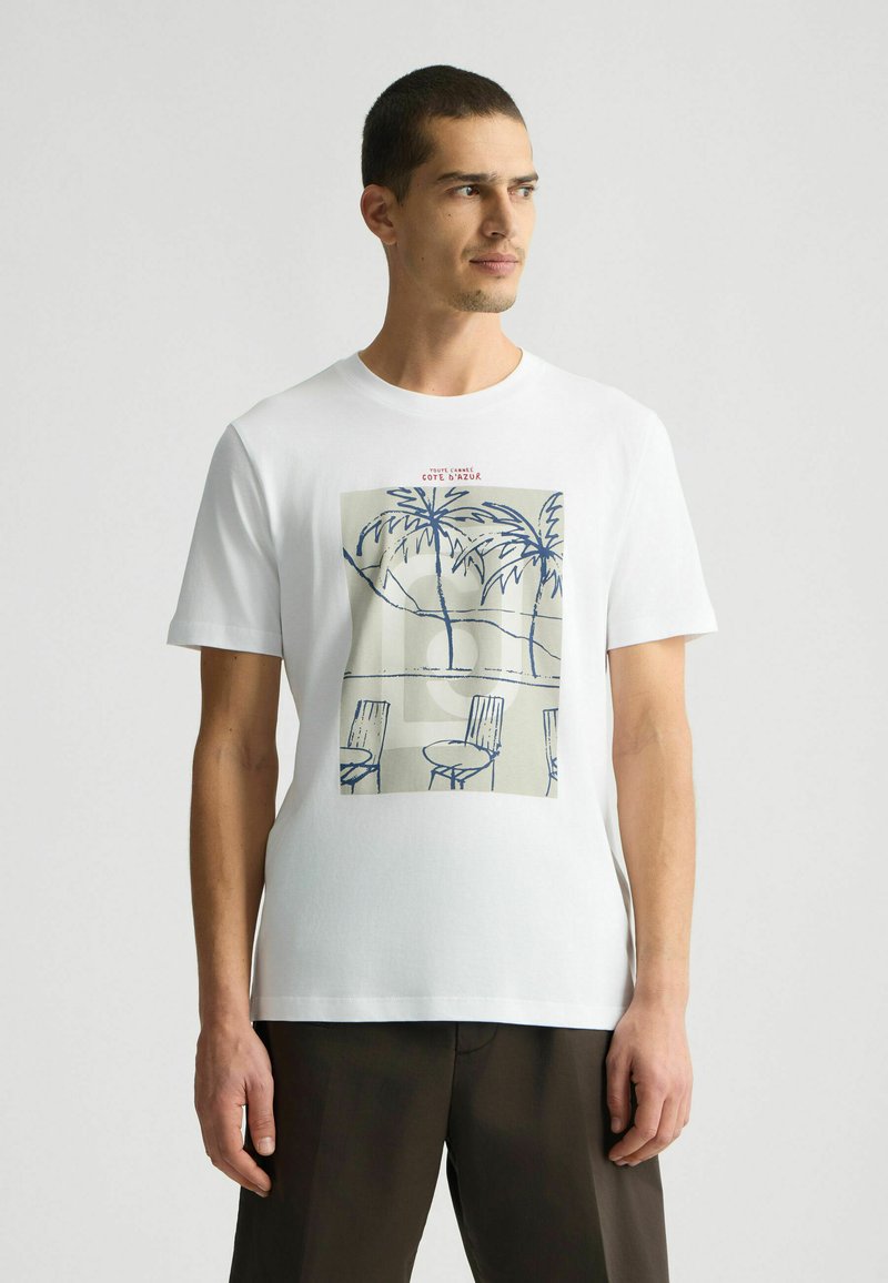 T-shirt alb din bumbac, cu un print grafic de palmieri și scaune în nuanțe de albastru și bej. Guler rotund și mâneci scurte.