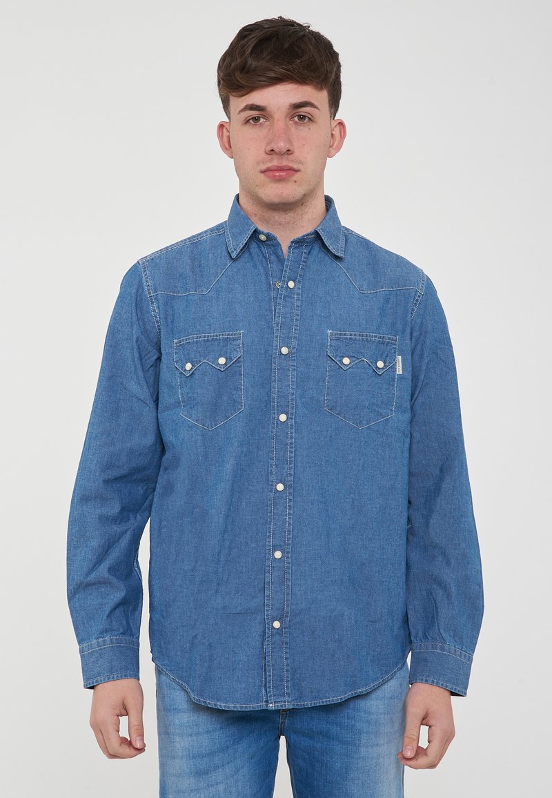 Camicia button-up in denim, blu chiaro, maniche lunghe, due tasche sul petto con alette appuntite, bottoni a pressione, cuciture semplici lungo le cuciture.