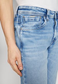 Lichtblauwe spijkerbroek met een slim fit, vijf zakken en zilverkleurige hardware. Opvallende vervaging en wassing details aan de voorkant.