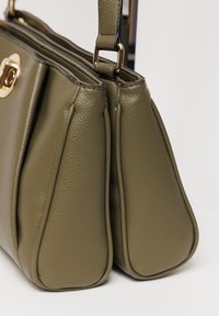 Borsa a mano in pelle verde oliva con finitura testurizzata, dotata di hardware color oro e una forma strutturata. Due scomparti offrono ampia spaziosità.