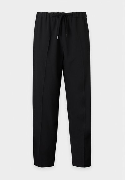 Μαύρο παντελόνι ίσιας γραμμής με ελαστική μέση και κορδόνι, απλωμένο πάνω σε απλό φωτεινό φόντο.