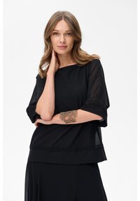 Czarna bluzka z lekkiego materiału, z krótkimi rękawami i luźnym krojem. Posiada dekoracyjne koronkowe wykończenie i subtelne, błyszczące detale.