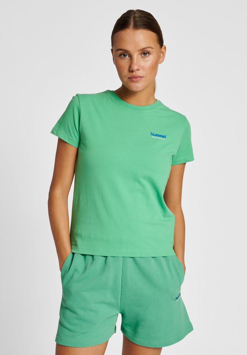 Grøn bomulds t-shirt med rund hals og korte ærmer, parret med matchende grønne shorts med sidelommer og et logo.