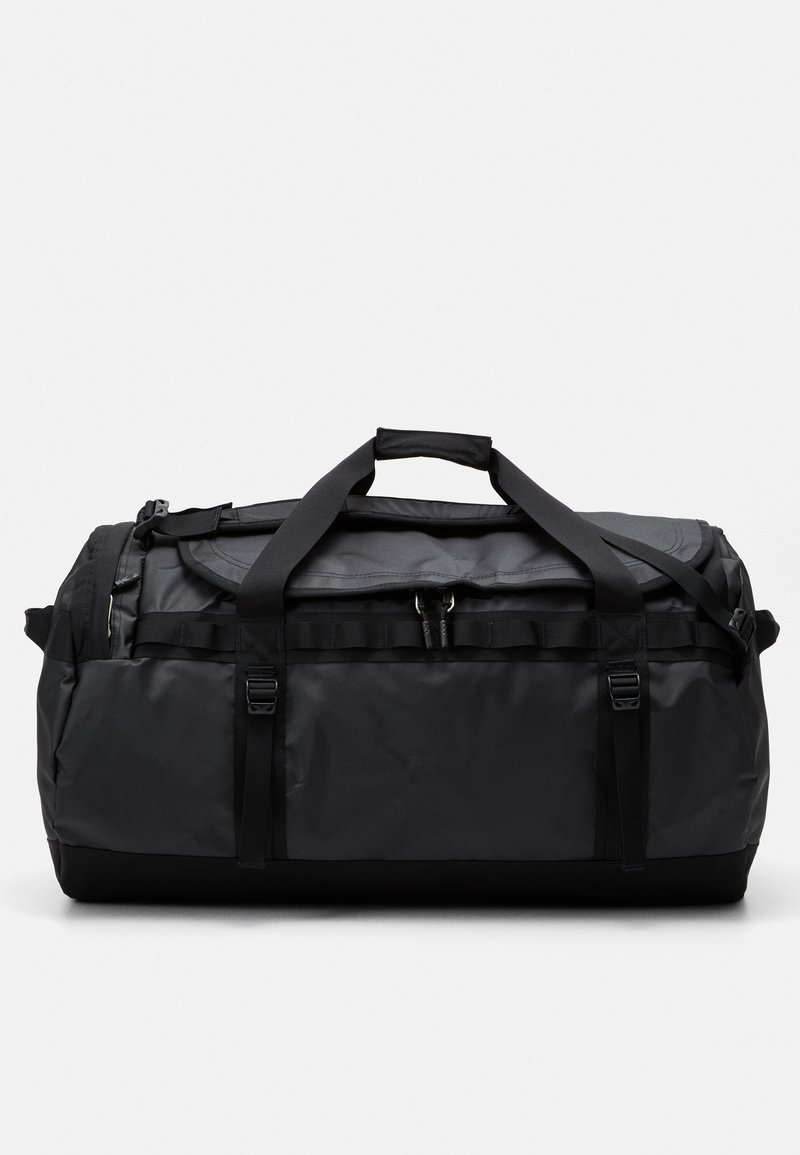 Svart duffelbag laget av slitesterkt stoff, med sterke håndtak, glidelåser og justerbare stropper. Rektangulær form med en jevn tekstur.