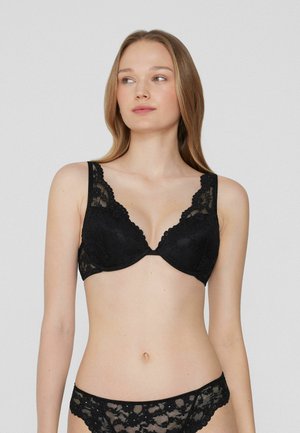 Soutien-gorge en dentelle noire avec des bords festonnés, des bonnets souples et des larges bretelles. Présente un motif floral et une finition lisse.