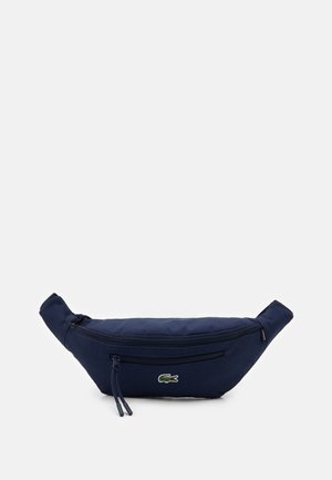 Navy blue fabric waist bag with two zippered compartments and a small green crocodile logo on the front center.