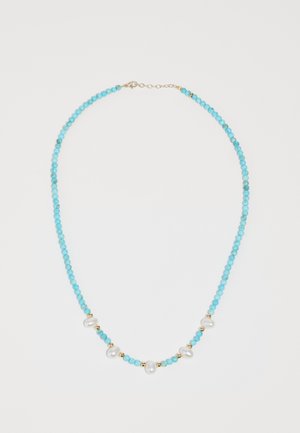Collier en perles turquoises avec des accents en or et des perles blanches irrégulières, présentant un design simple et une fermeture à clip.