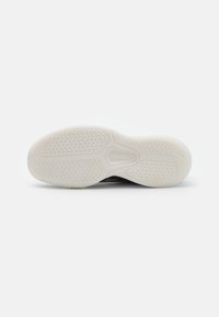 White rubber sole with textured grip pattern and a smooth exposed section. Black upper material not visible in the image.