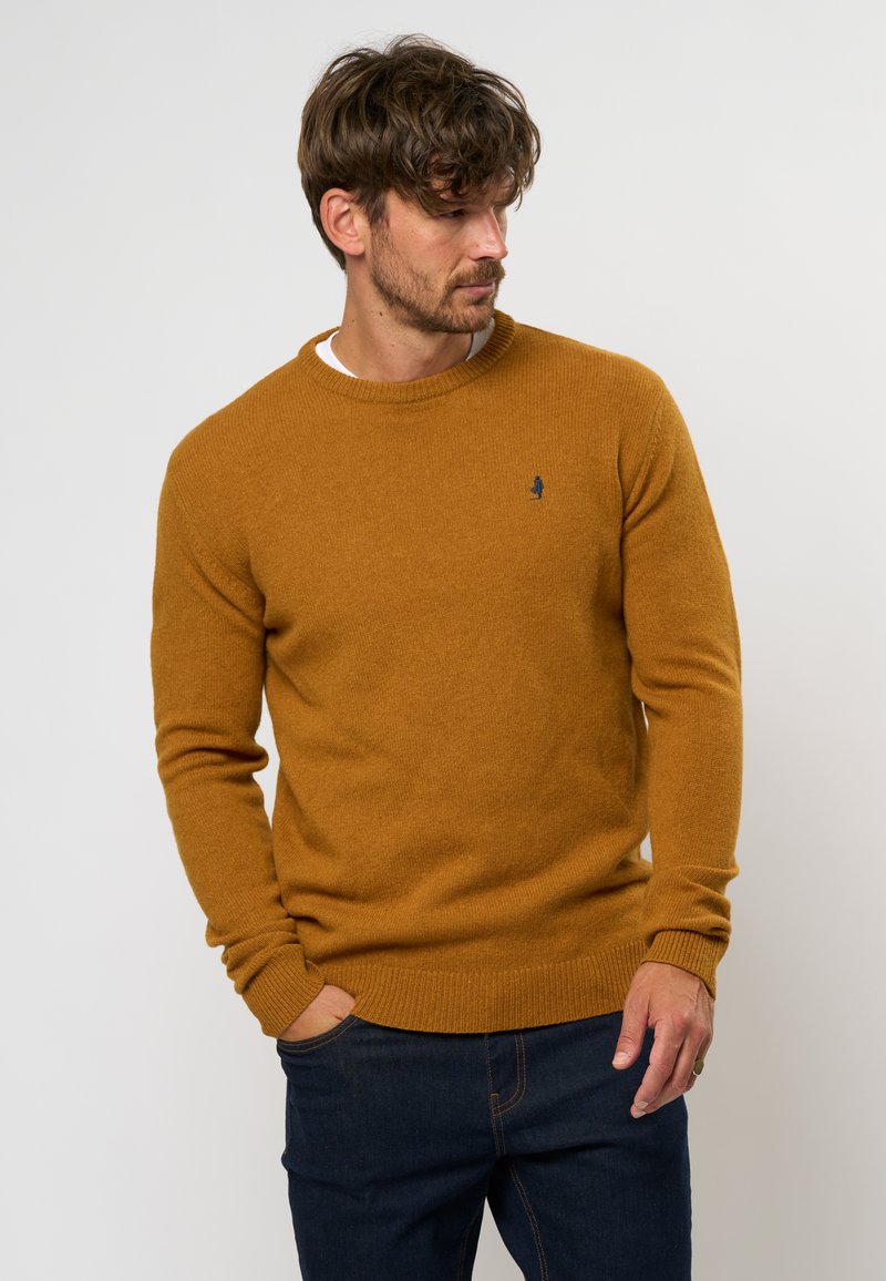 Senfgelbes Sweatshirt mit klassischem Rundhalsausschnitt, gerippten Bündchen und Saum. Einfaches Design mit kleinem blauen Logo auf der Brust.