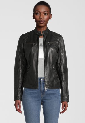 Schwarze Lederjacke mit Stehkragen, Reißverschlusstaschen und tailliertem Design. Trägt man über einem grauen Shirt, kombiniert mit hellblauen Jeans.