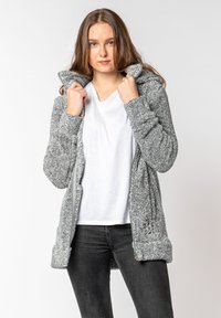 Gray, textured fleece jacket with a hood, front zipper, and side pockets. Worn over a white T-shirt and paired with dark jeans.