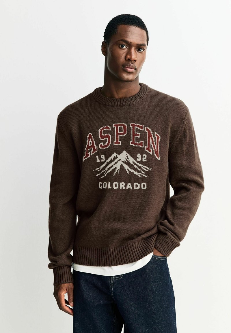 Brązowy sweter z dzianiny z napisem "ASPEN" i "COLORADO" w białym i czerwonym kolorze, z graficznymi detalami gór oraz ściągaczami na mankietach i dołem.