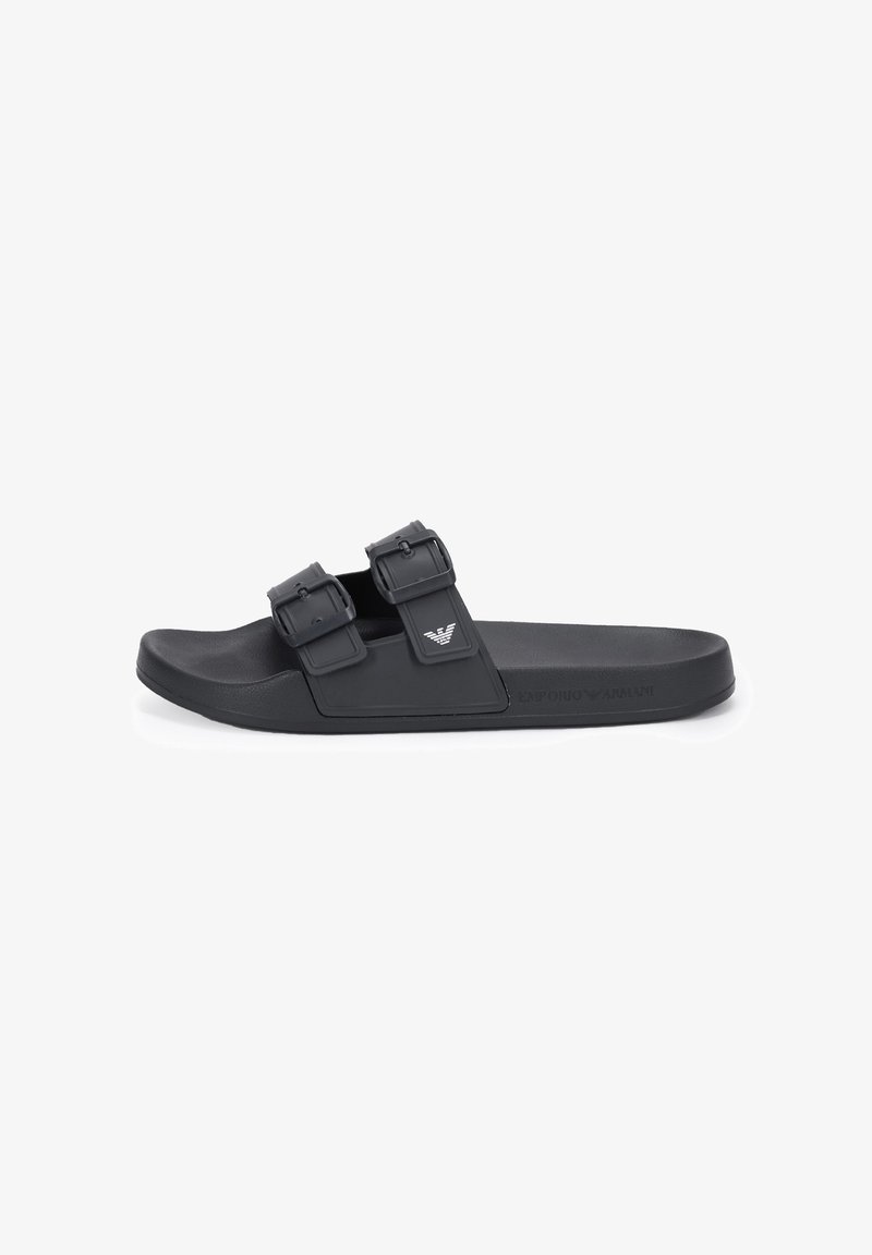 Black slide sandal with two adjustable buckle straps and a logo on the upper strap, featuring a flat sole and embossed brand name on the side.