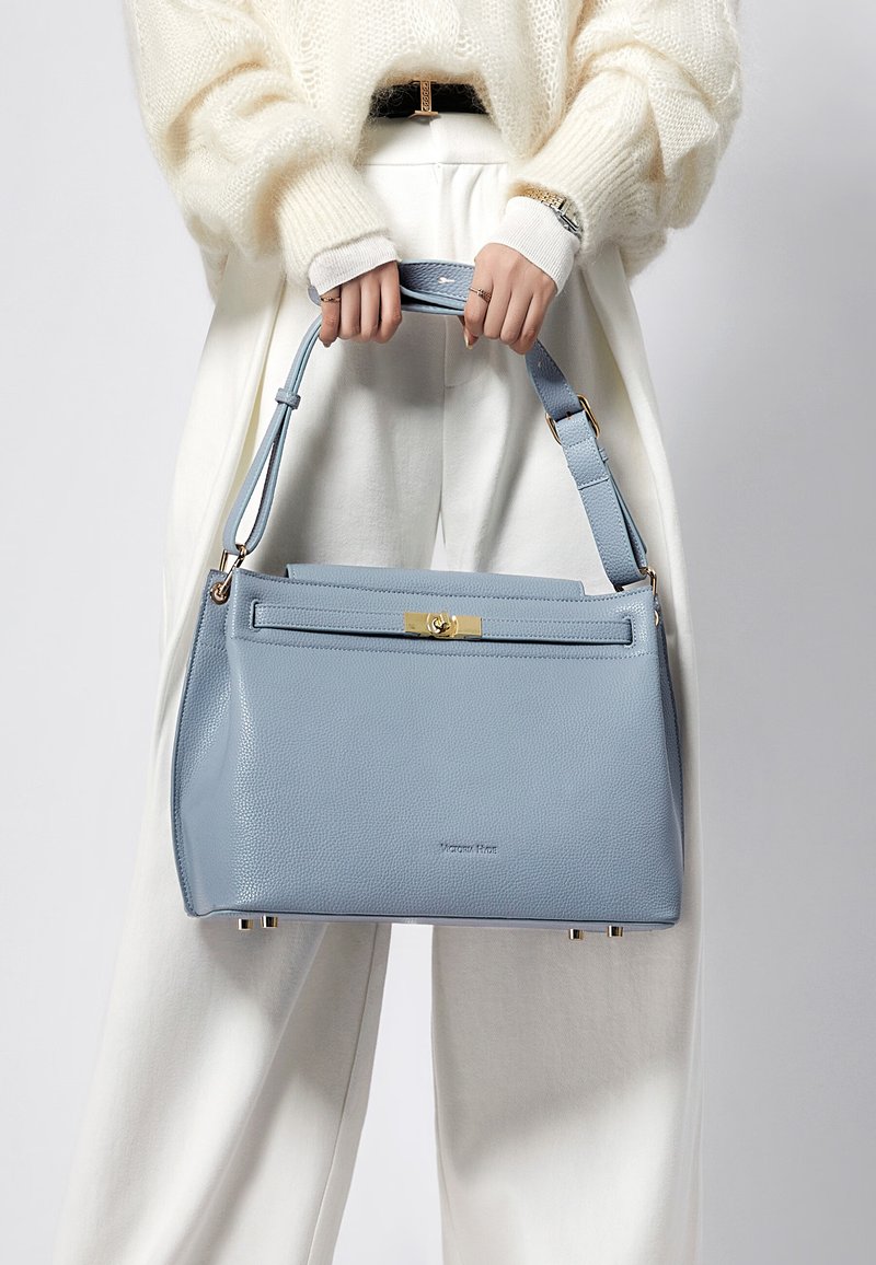Ljusblå läderhandväska med strukturerad form, guldfärgade beslag och avtagbar rem. Mjuk textur och dragkedja upptill.