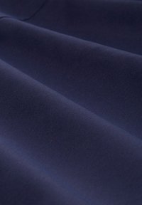 Tmavě modrá látka s hladkou texturou, na které jsou jemné záhyby a konzistentní vzor, naznačující materiál střední hmotnosti.