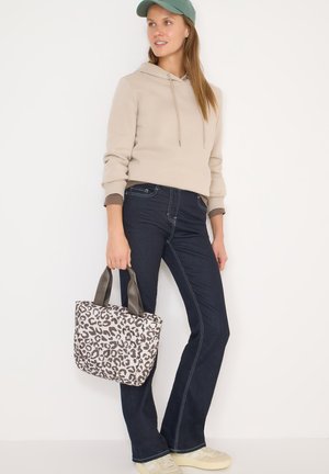 Beige capuchontrui met een kangeroezak, donkere spijkerbroek en een bruin handvat leopardprint draagtas. Casual sneakers.