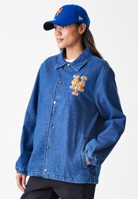 Modrá džínová bunda s knoflíkovou přední částí, patentními knoflíky, postranními kapsami a vyšitým oranžovým logem "NY" na hrudi.