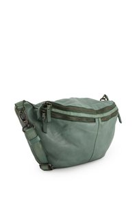 Zelená kožená crossbody taška s několika zipovými přihrádky, zaoblený tvar, texturovaný povrch a nastavitelný popruh.