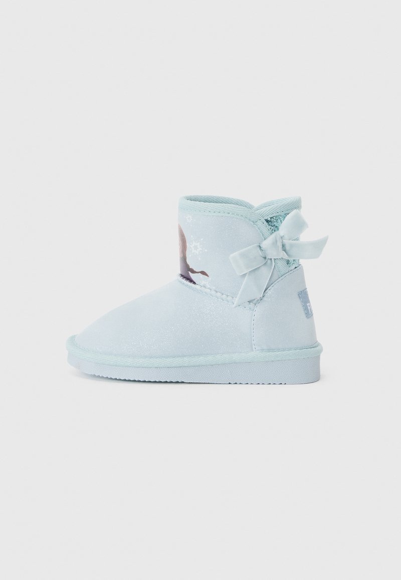 Botte d'hiver pour enfant bleu clair avec finition pailletée, nœud latéral et motif partiel de renne et de flocon de neige sur la cheville.