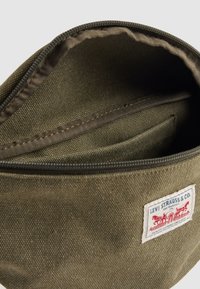 Olijfgroene canvas pouch met een ritssluiting en een binnenzak, voorzien van een Levi Strauss & Co. merkpatch aan de voorkant.