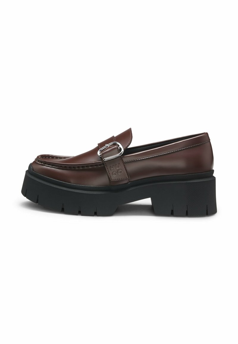 Mocassin en cuir marron avec semelle épaisse noire à crampons et détail de boucle argentée sur le côté, embossé avec le logo "HUGO".