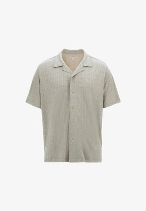 Polokošeľa s krátkym rukávom vo svetlo béžovej farbe s textúrovaným diamantovým vzorom, s golierom a piatimi gombíkmi na prednej strane.