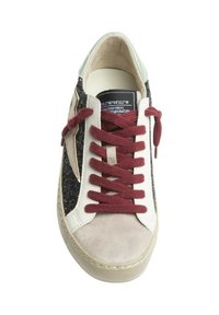 Zapatilla con una mezcla de materiales: purpurina negra, ante crema y cuero beige. Presenta cordones burdeos y un acento verde en el talón.