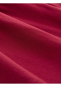 Tissu bordeaux avec une surface lisse et légèrement texturée, présentant un léger gauffrage, mettant en valeur un tombé fluide et une couleur riche et profonde.