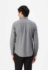 Long-sleeve, button-down shirt in gray checkered pattern. Features a standard collar, rounded hem, and button cuffs. Made of lightweight fabric.