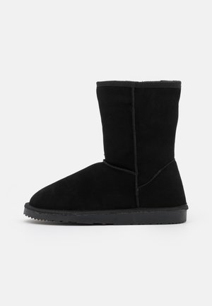 Bottines en daim noir avec un bout rond et une texture lisse, dotées d'une couture et d'une semelle en caoutchouc plate.