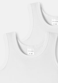 To hvide tanktoppe med rund halsudskæring og brede stropper, der har en glat tekstur og flade sømme. Labels er synlige indeni.