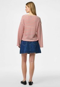Maglietta a righe rosse e bianche con maniche lunghe abbinata a una gonna di jeans blu scuro. L'outfit presenta una vestibilità comoda e un design semplice.