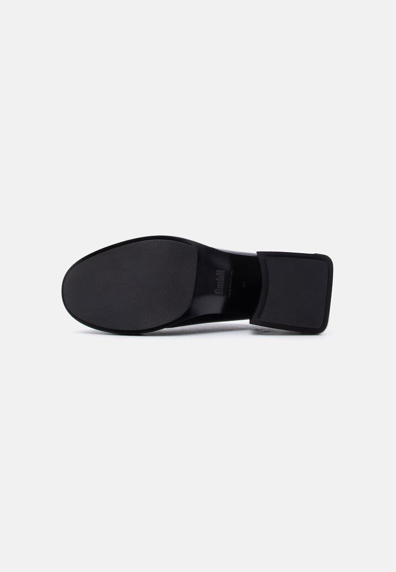 Black shoe sole with textured front and smooth square heel visible against white background.