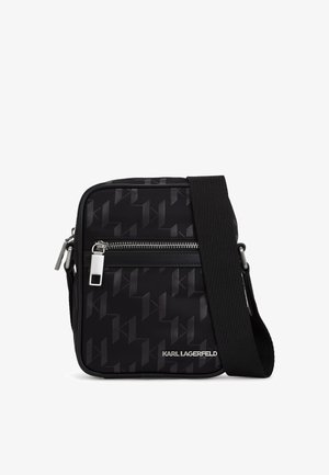 Musta ristiõlakott, millel on tekstureeritud muster, hõbedased detailid, lukuga sulgemine ja reguleeritav rihm. Logo on esiküljel.