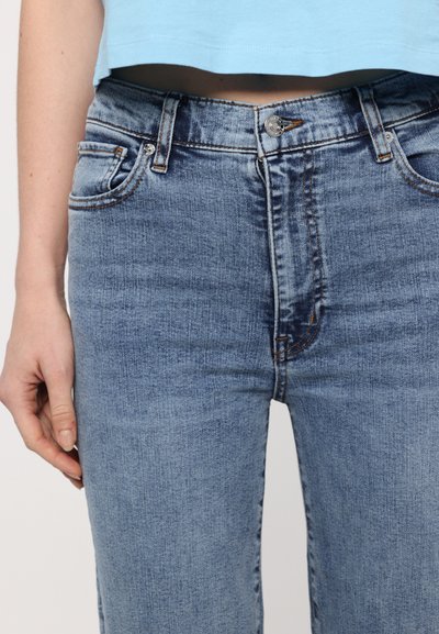Hellblaue Jeans aus Denim mit hoher Taille, fünf Taschen-Design und kontrastierenden Nähten. Glatte Oberfläche mit verwaschenem Finish.