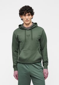 Oliwkowa zielona bluza z kapturem i kieszenią z przodu; na piersi czarne logo „EA7”; w komplecie z dopasowanymi spodniami.