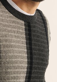 Maglione a maglia grigio e nero con un motivo testurizzato, con strisce orizzontali e scollo rotondo, che presenta lievi contrasti di colore.