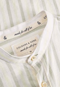 Camicia a righe verde chiaro e crema con colletto, dotata di bottoni e un'etichetta con la scritta "Colours & Sons" e taglia M.