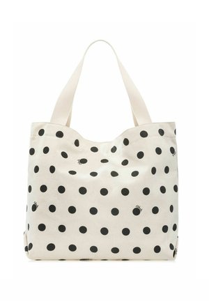 Biała torba na ramię wykonana z materiału typu płótno z dużymi czarnymi groszkami i dwoma szerokimi paskami na ramiona na jednolitym tle.